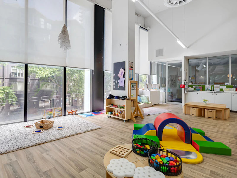 Sala ampla e iluminada com brinquedos de movimento e grandes janelas