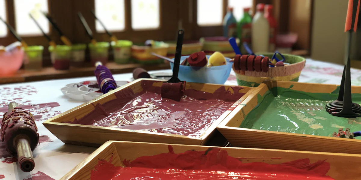 Bandejas de tinta guache em tons quentes sobre uma mesa de ateliê