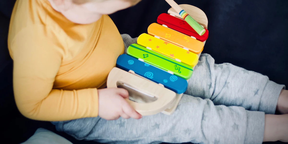 Criança pequena tocando um xilofone de madeira colorido