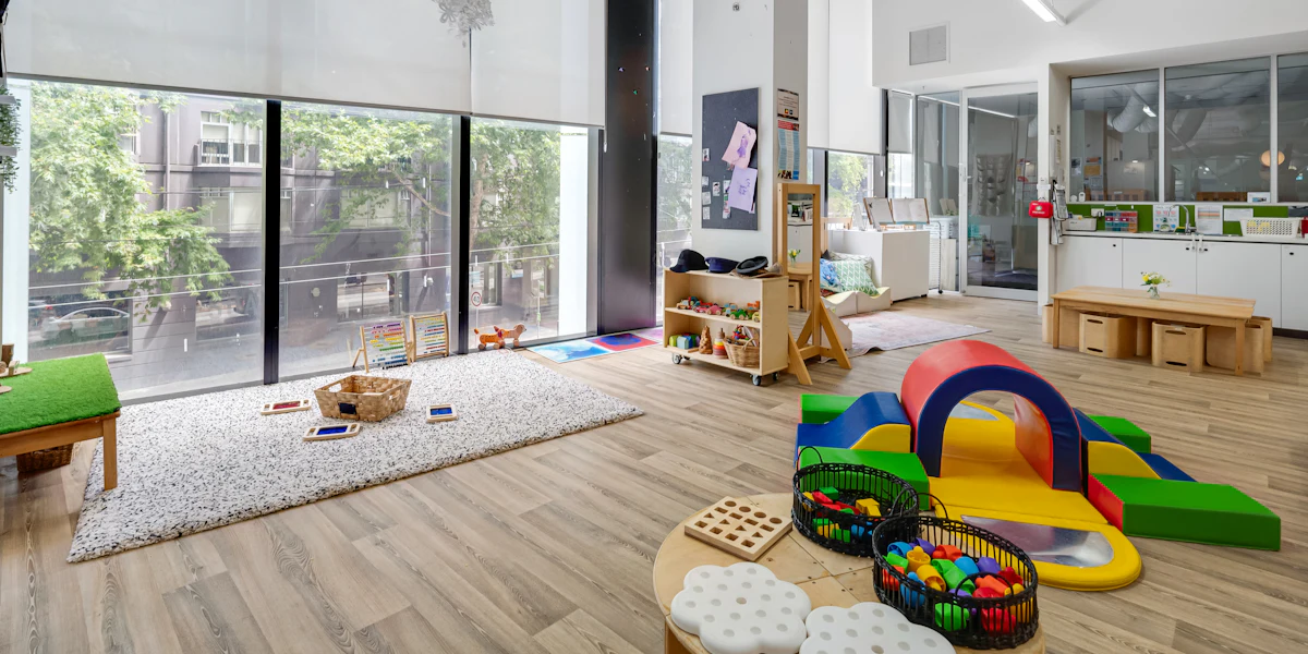 Sala ampla e iluminada com brinquedos de movimento e grandes janelas